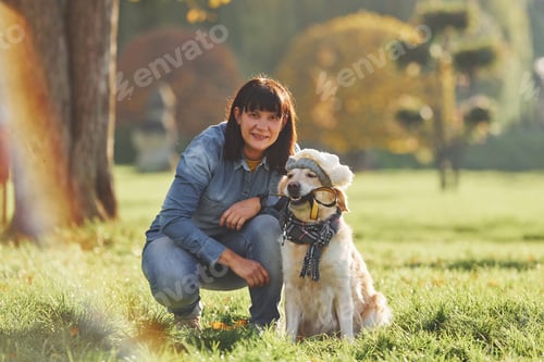 Preview: Woman have a walk with Golden Retriever dog in the park at daytime