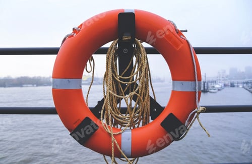 Preview: Orange lifebuoy hanging on the railing in the harbor.