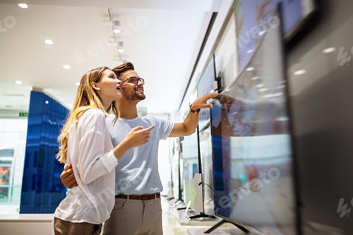 Preview: Young couple in consumer electronics store looking at latest digital devices, television.