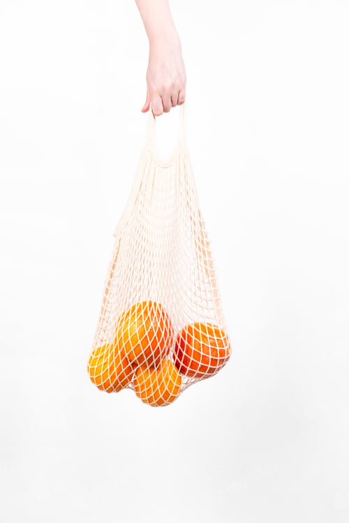 Preview: Woman's hand is on hold string bag with oranges and grapefruits. Concept zero waste, eco-friendly
