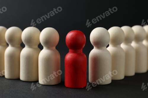 Preview: Competition concept. Red human figure among wooden ones on black background, closeup