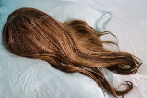 Preview: Closeup of a brunette wig with highlights on a silk pillow