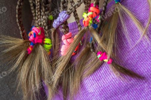 Preview: Close up of braid hair of little girl with colorful rubber bands
