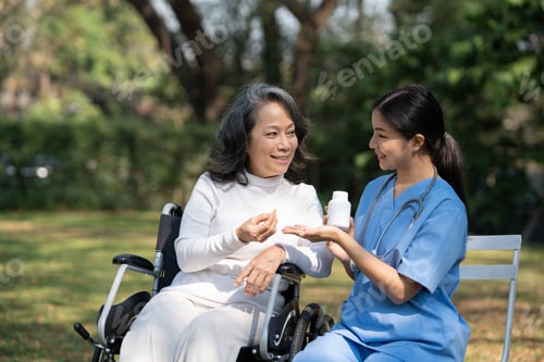 Vista previa: Young Asian nurse giving medicine to senior woman, explaining the details of the pills to an old