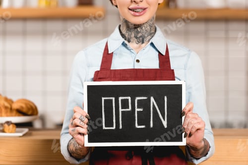 Preview: partial view of barista holding signboard with open inscription in coffee shop