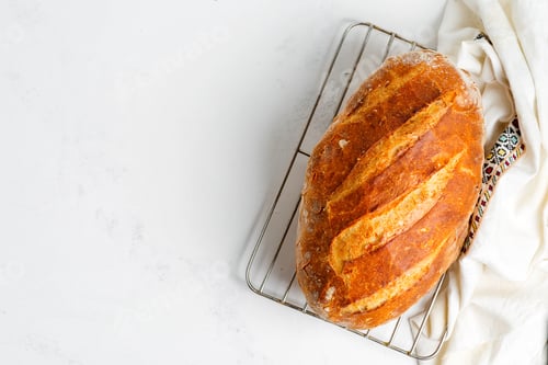 Preview: Freshy baked homemade bread on a light grey marble table decorated textile towel