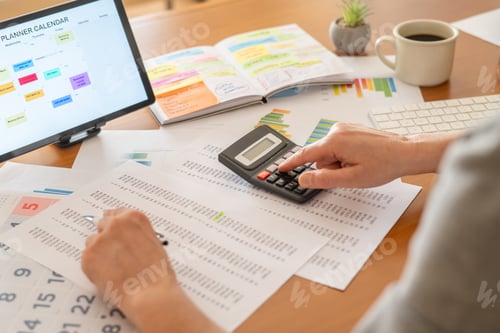Preview: Person calculating finances at a desk with calculator,planning for business or personal goals