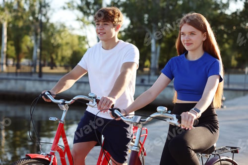 Preview: Teenage girl and boy riding bicycles on city street