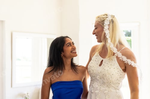 Preview: Bride and bridesmaid sharing joyful moment, smiling and celebrating wedding day