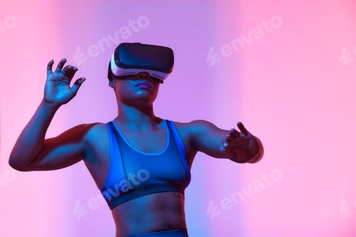 Preview: African american woman streamer playing video game using virtual reality glasses at gaming room