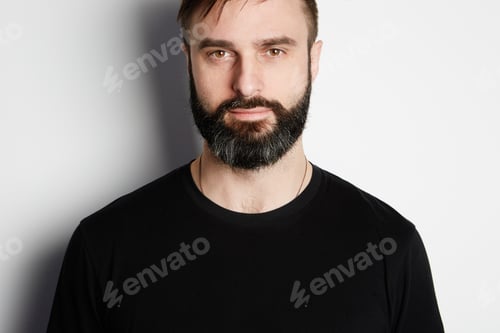 Preview: Portrait of bearded man in black tshirt on the empty background