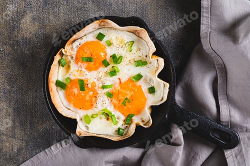 Preview: Close up of homemade scrambled eggs in pita bread with herbs in a frying pan on the table top view