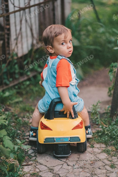 Preview: Little baby boy riding car in garden