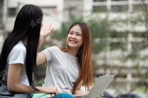 Preview: Cheerful students celebrating collaboration with a high-five in an outdoor study space