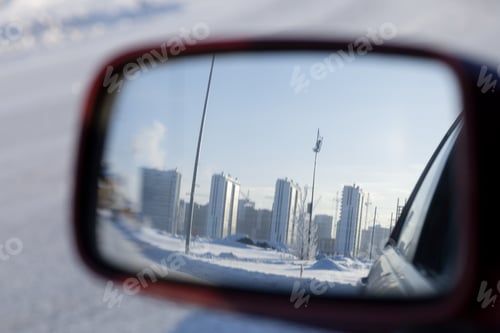 Preview: Reflection of the cityscape in the rear-view mirror of the car on a frosty winter day