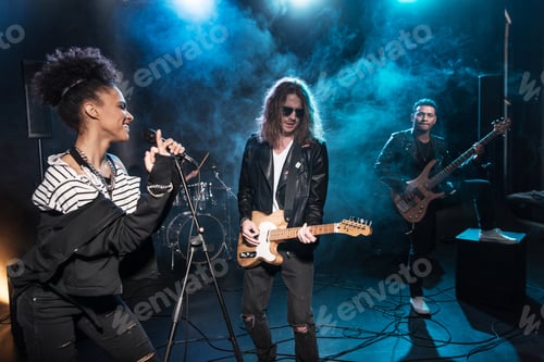 Preview: Female singer with microphone and rock and roll band performing hard rock music on stage