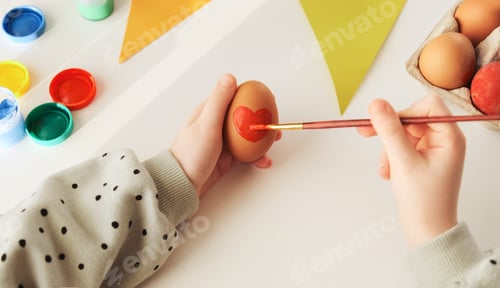 Preview: Little child decorates Easter eggs with colored food paint. Preparing forthe holy Easter.