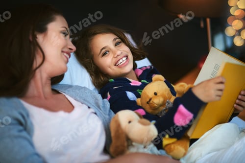 Preview: One more story before bedtime. Mother and daughter reading together in bed.