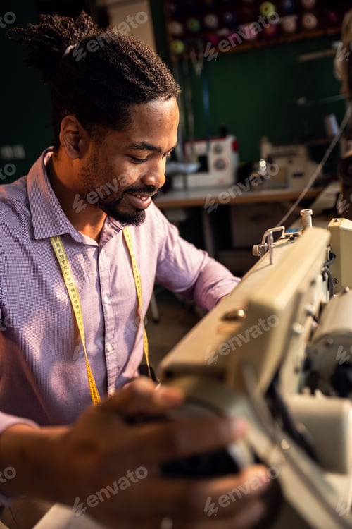 Preview: Male fashion tailor working on the sewing machine for the suit design in his workshop.