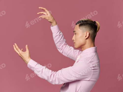Preview: A man of Asian appearance is gesturing with his hands fashionable hairstyle in a pink shirt