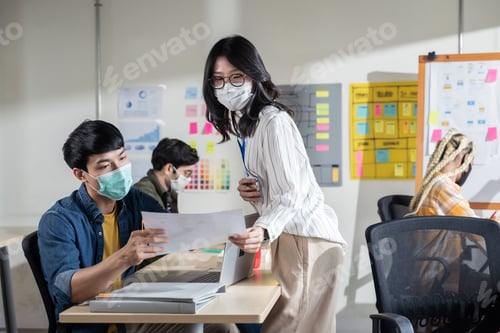 Preview: Asian creative business team working after lockdown with protective face mask.