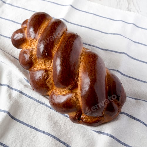 Preview: Homemade jewish challah bread on cloth, side view. Closeup.