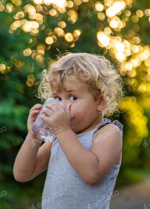 Preview: A child drinks water from a glass. Selective focus.