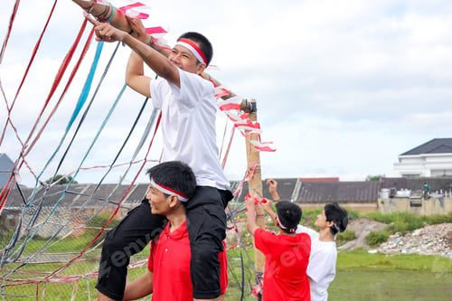 Preview: Young People Smiling And Collaborating To Decorate Bamboo Pole