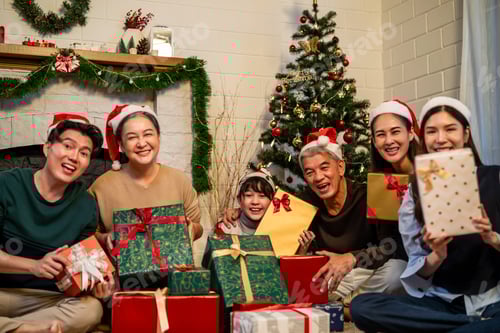 Preview: Portrait of Asian family exchanging presents during christmas at home.