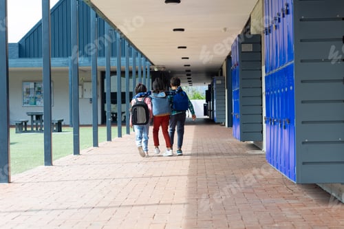 Preview: Three children walk down a school corridor, arms around each other, with copy space