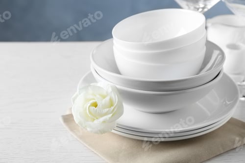 Preview: Dishware, napkin and eustoma flower on light table, space for text