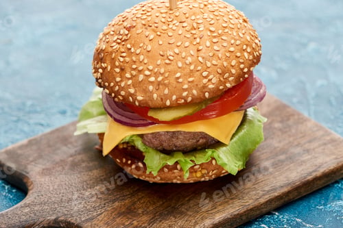 Preview: delicious cheeseburger on wooden board on blue textured surface