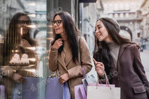 Preview: Two happy women windows shopping in a down town city