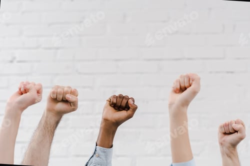 Preview: cropped view of multicultural people with clenched fists near brick wall