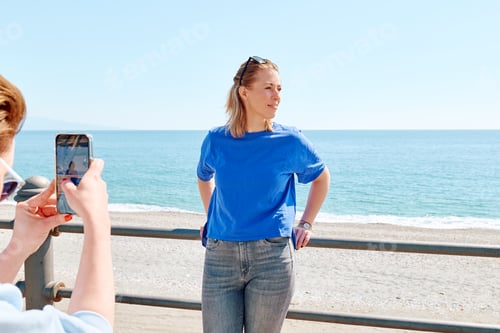 Preview: Young woman spend time at seaside, enjoy sunny day using smartphone to take photo of her friend