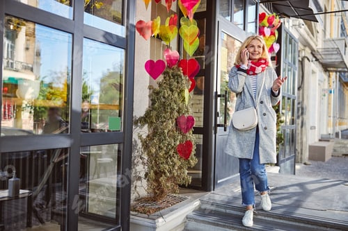 Preview: Adult stylish woman is using smartphone outdoors