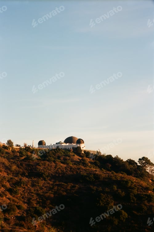 Preview: an observatory and telescope tower on a hilltop at sunset with a blue sky behind it