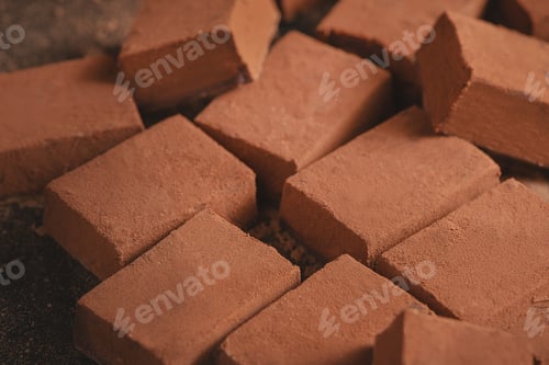 Preview: Cocoa powder texture close-up. Soft chocolates on a black background with copy space