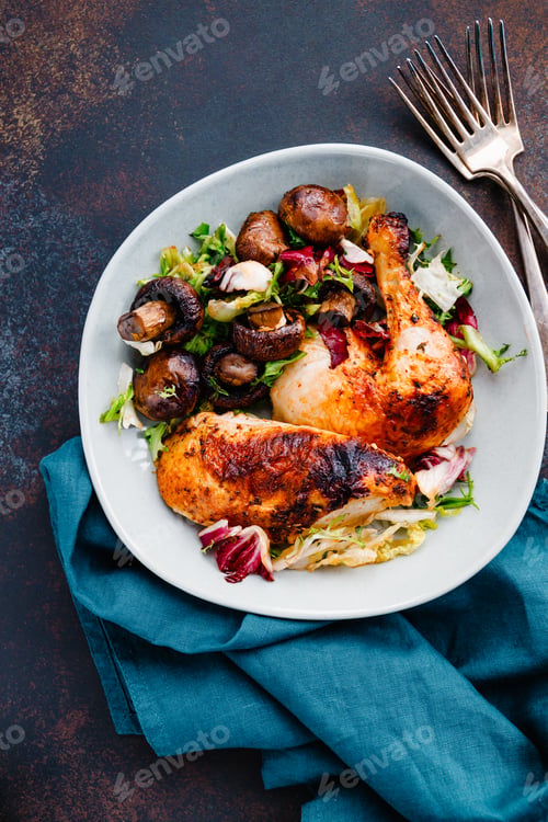 Preview: Roasted chicken leg and breast with fresh salad and champignons on a plate.