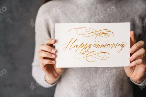 Preview: Happy beautiful girl smiling while showing happy anniversary card