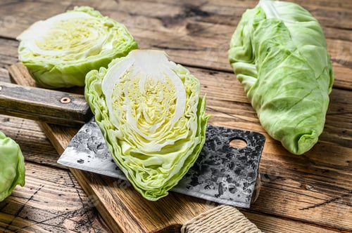 Preview: Raw Cutting Pointed white cabbage head on a cutting board. Wooden background. Top view