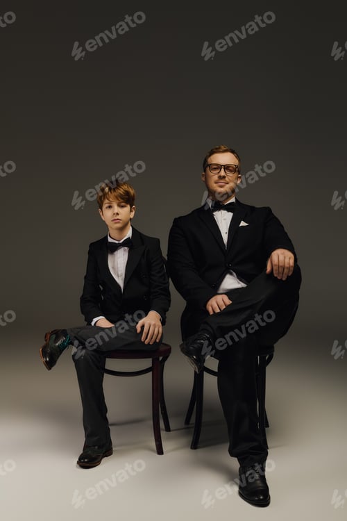 Preview: Elegant father and son duo showcasing timeless style in a sophisticated studio setting
