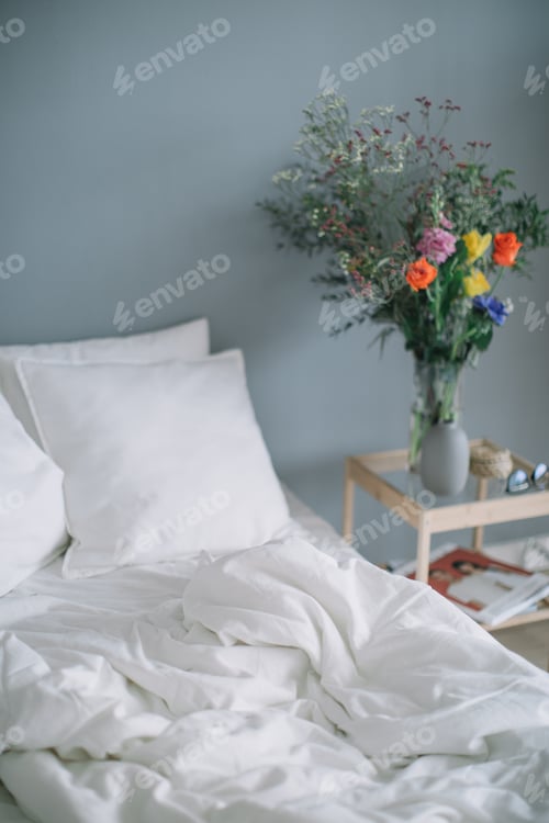 White Bed Linens and Flowers in Bedroom Interior