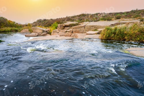 Preview: A small shining stream flows among smooth wet and dark stones