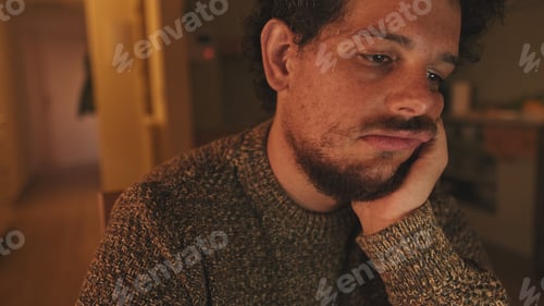 Preview: Close-up of guy sitting at table in the kitchen with laptop