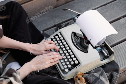 Preview: hands of a woman writer on the keyboard of a typewriter on the background of a wooden floor, copy