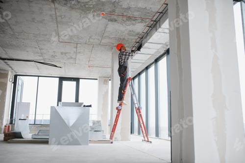 Preview: Construction worker installing ventilation system on a ladder in building under construction