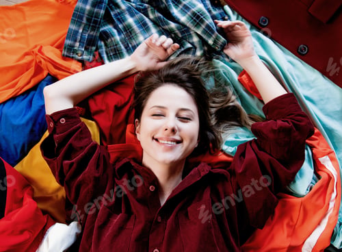 Preview: smiling girl in red shirt lies on her things.