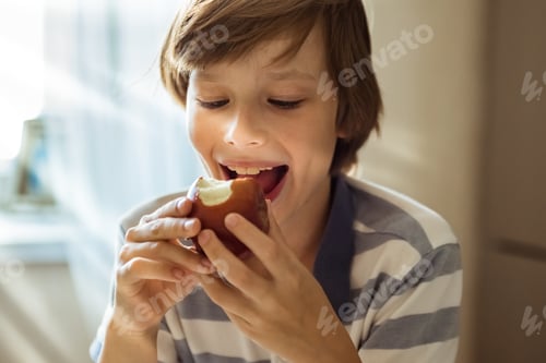 Visualização: Menino fofo morde maçã suculenta. O rosto de uma criança comendo lanche saudável, frutas maduras