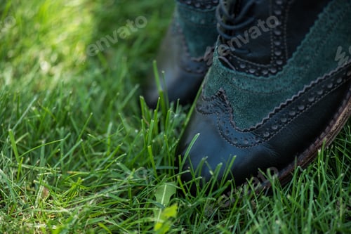 Preview: selective focus of black leather shoes on green grass
